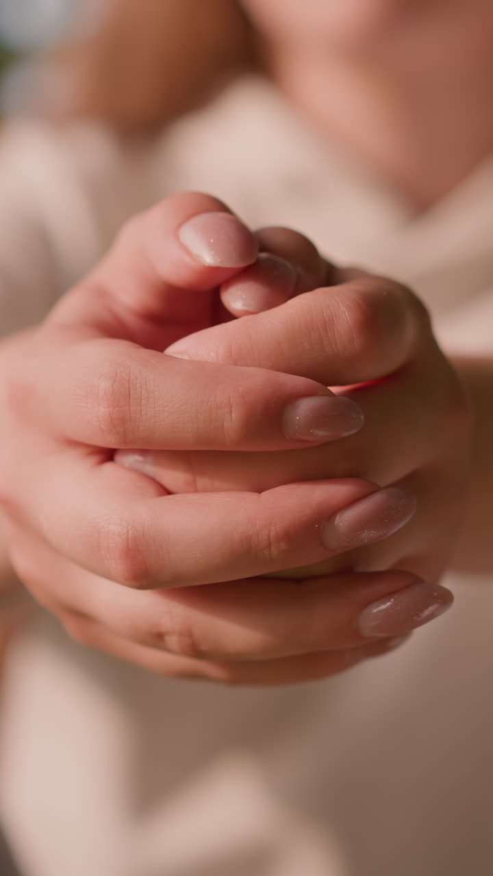 una joven se sienta al aire libre, con las manos juntas en una contemplación tranquila, con un fondo borroso con vegetación y luz solar que emite un suave resplandor