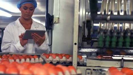 personal femenino que utiliza una tableta digital junto a la línea de producción