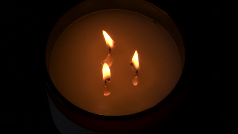 4k, cámara lenta, tres velas encendidas con fondo oscuro
