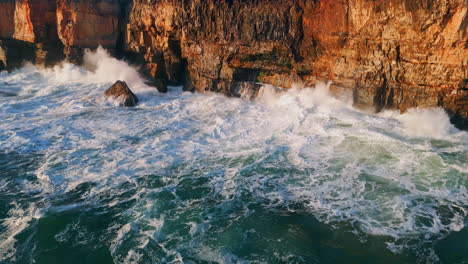 drone powerful ocean waves breaking on high coastal rocks with bubbling foam.