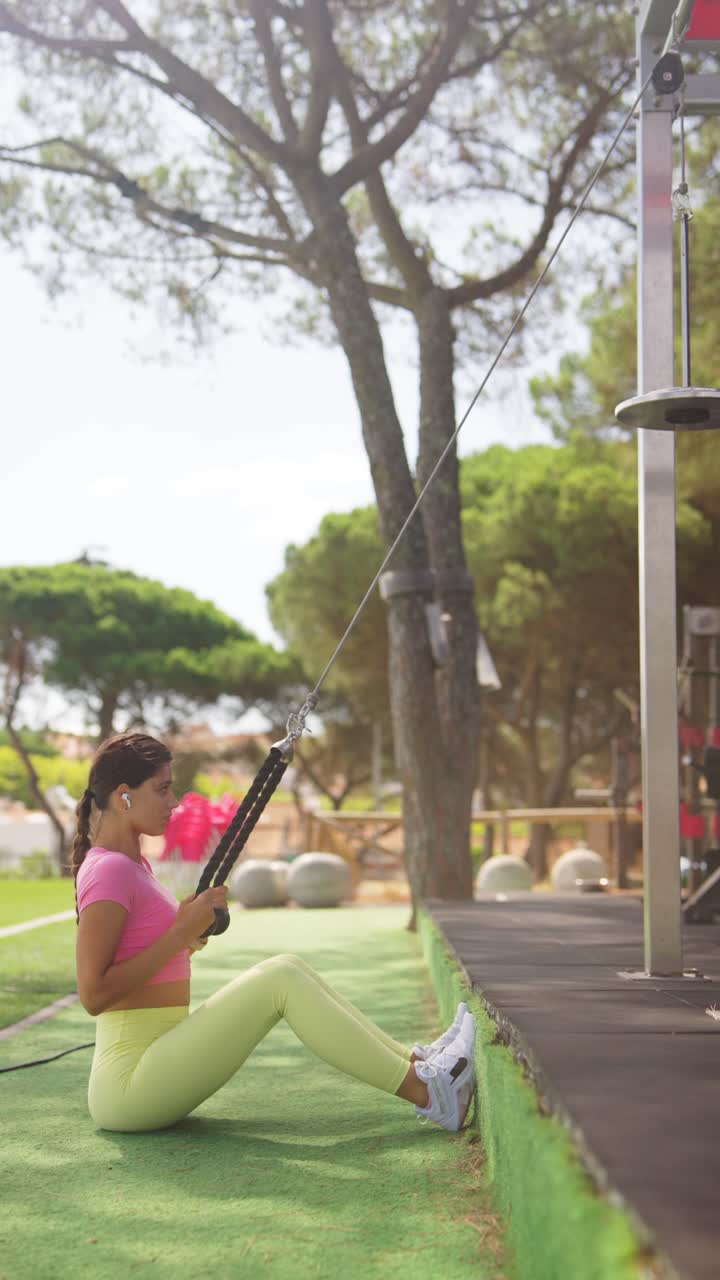 A woman exercising with a cable machine at an outdoor gym