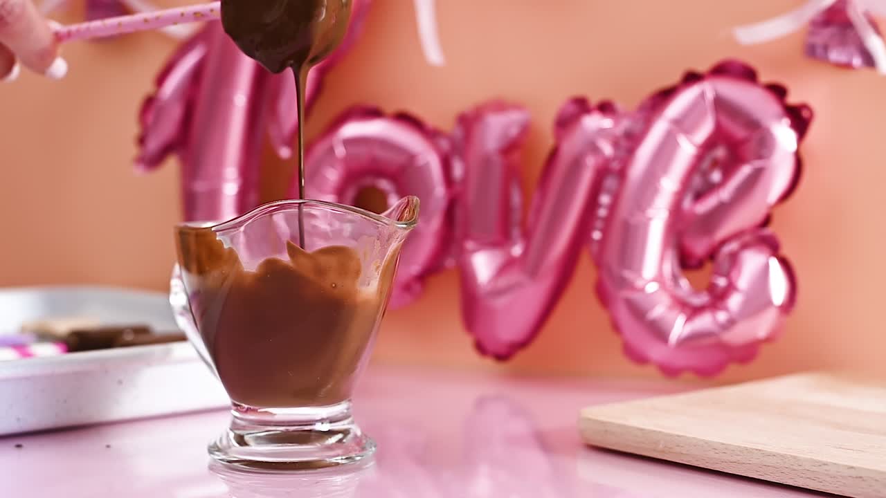 Immergere cake pops nel cioccolato fondente nero e preparare biscotti dolci per San Valentino. Slow motion