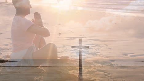 video of crucifix over senior caucasian praying woman on the beach