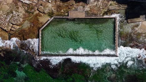 aerial top down of rock pool surrounded by waves and rocky shoreline in cronulla, sydney nsw australia