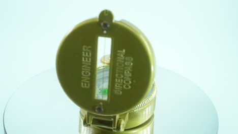 a close up shot of a golden retro opened compass on a reflecting rotating stand, 360 degrees, green arrow, studio lighting, slow motion, 4k video