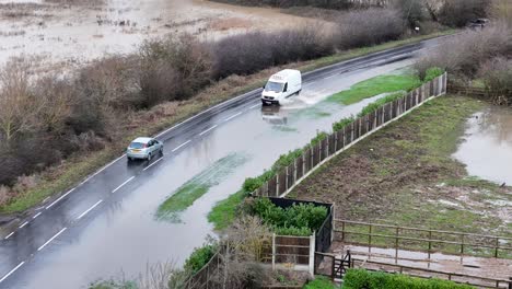 vehicles drive through flooded road abridge essex uk aerial