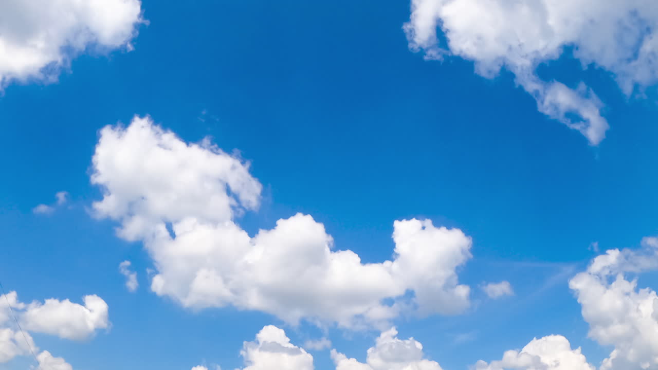 Amazingly beautiful azure sky with some white clouds. Cotton clouds changing shapes quickly. Low angle view. Timelapse.
