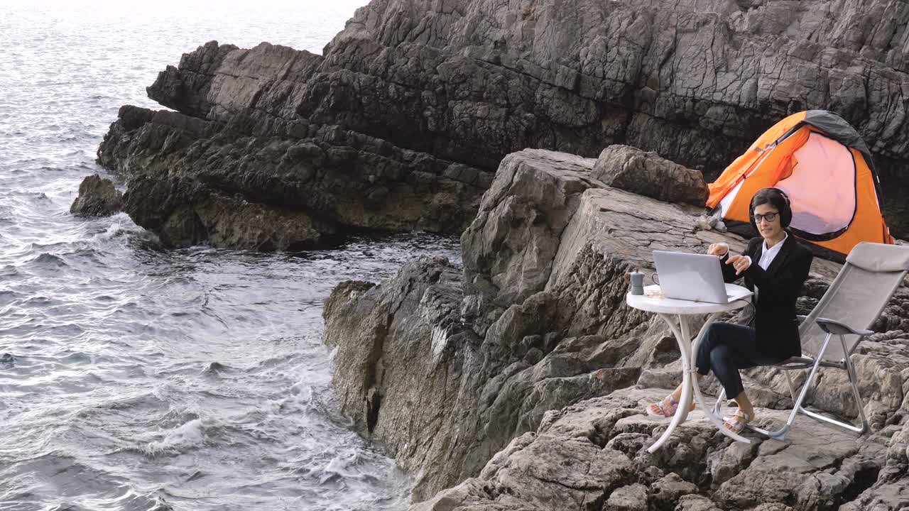 해변에 앉아서 파트너와 온라인 채팅을 하는 여성 사업가.