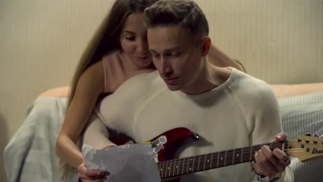 couple playing guitar together at home