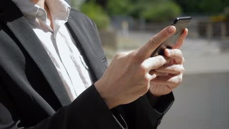 Side-view-of-young-Caucasian-male-hands-texting-on-phone-outside