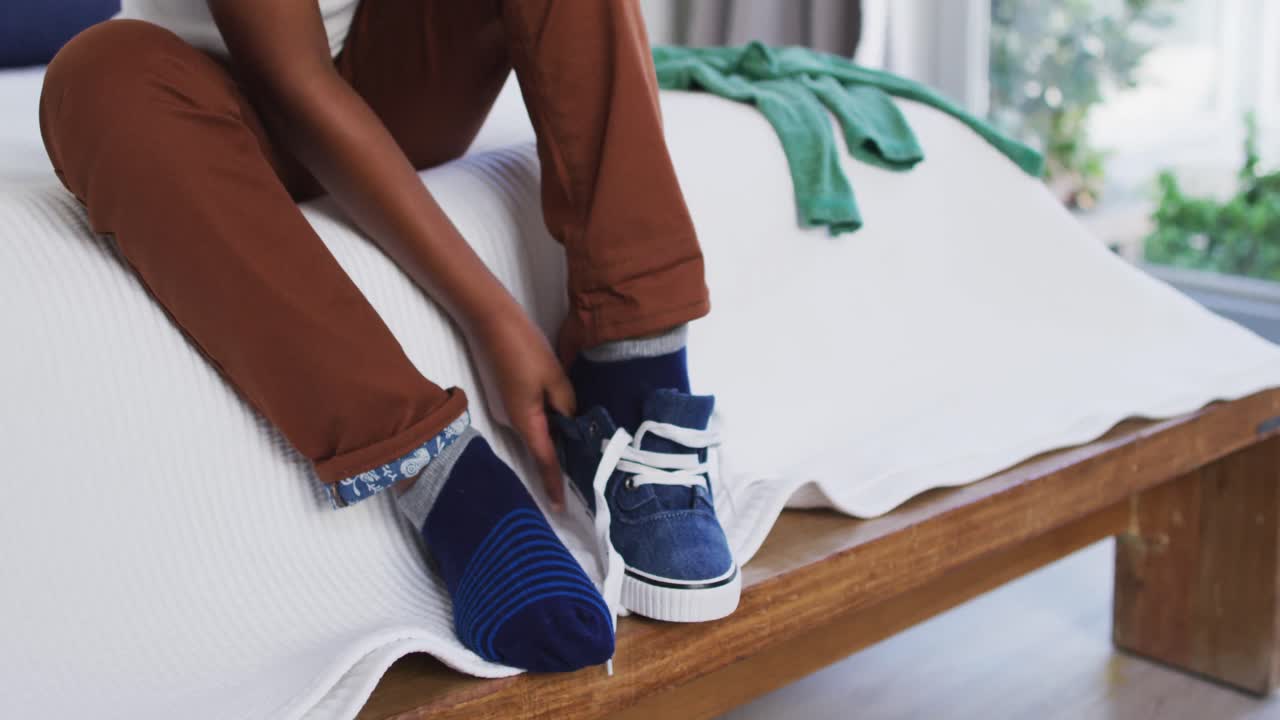 chico afroamericano de pie en el dormitorio vistiéndose