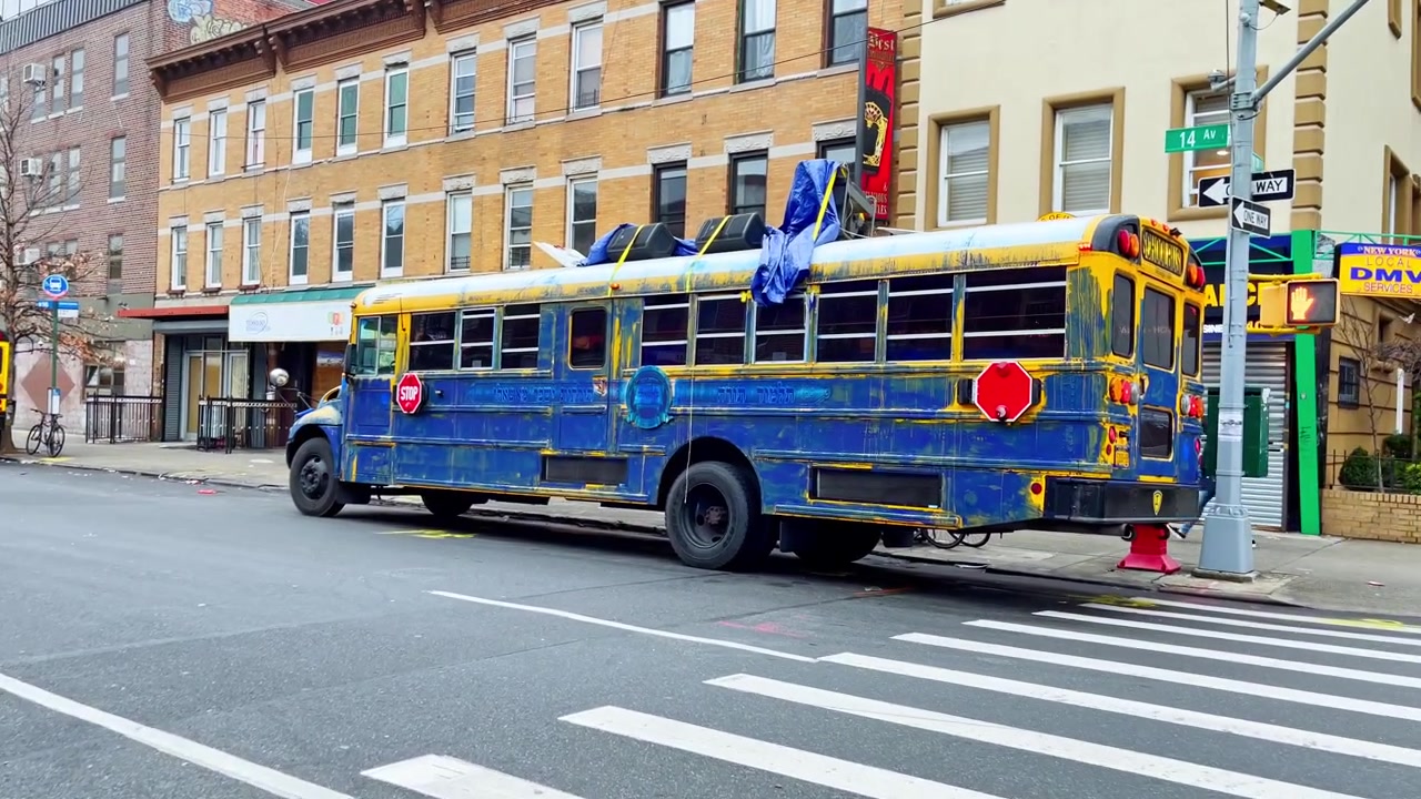 New York, USA, 9 March 2022: Blue painted bus parked near 14 Avenue corner. Blue and yellow bus with Hebrew text parked at 14 Avenue corner, crosswalk and signs visible.