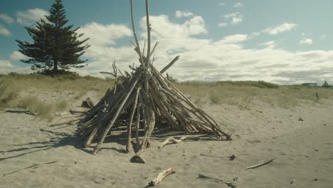 ramas de árboles haciendo una pirámide en la playa para una hoguera