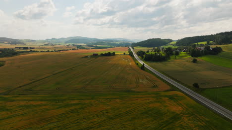 Vista-Aérea-De-La-Carretera-A-Lo-Largo-De-Campos-De-Trigo-En-Noruega.