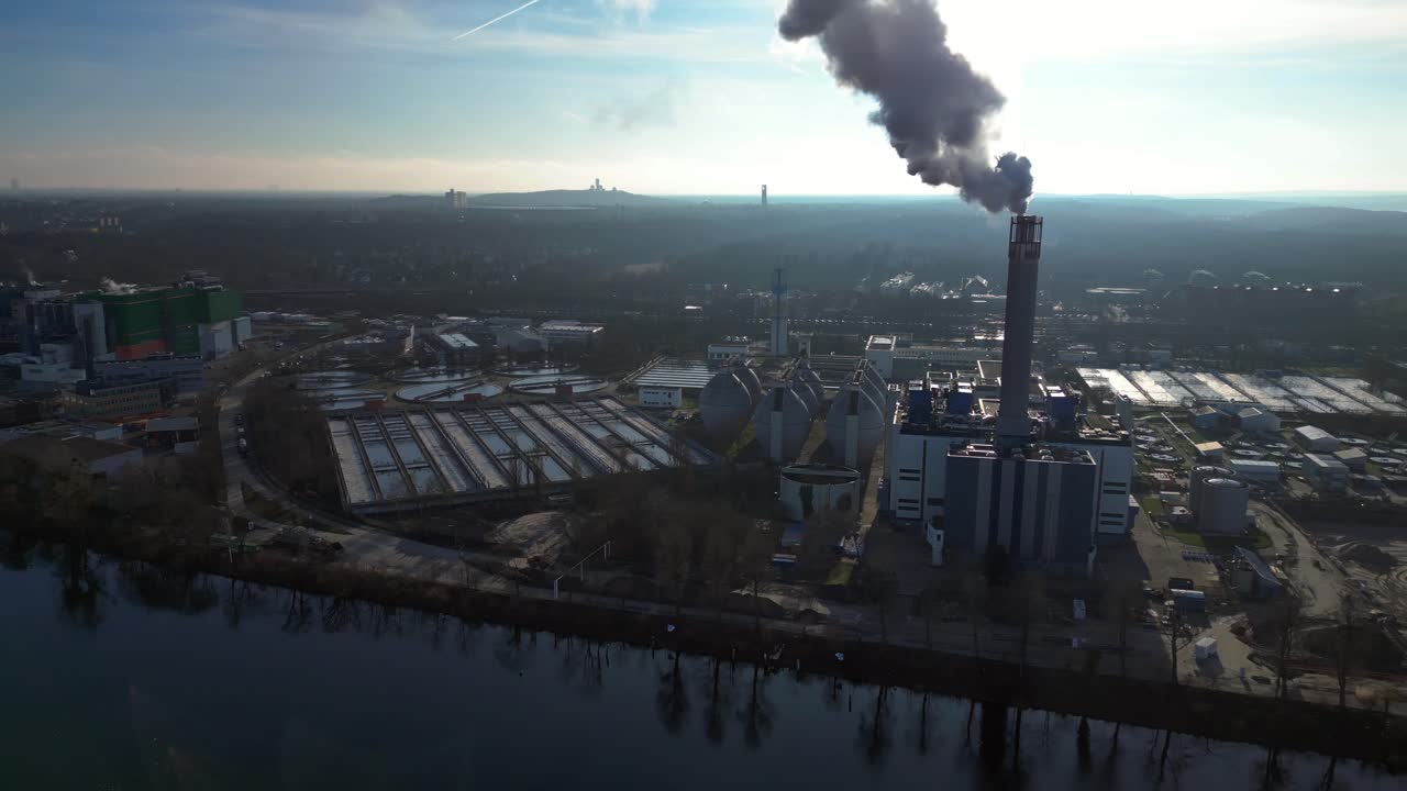 Waste to energy plant emitting smoke from its chimney, located near an urban area, environmental impact of waste. Amazing aerial view flight panorama overview drone