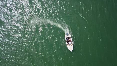 aerial top down tracking shot of motor boat speeding away in a circle