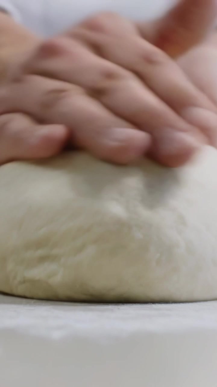 Vertical video: Shaping chef hands folding dough ball on floured counter for proofing, chef jacket
