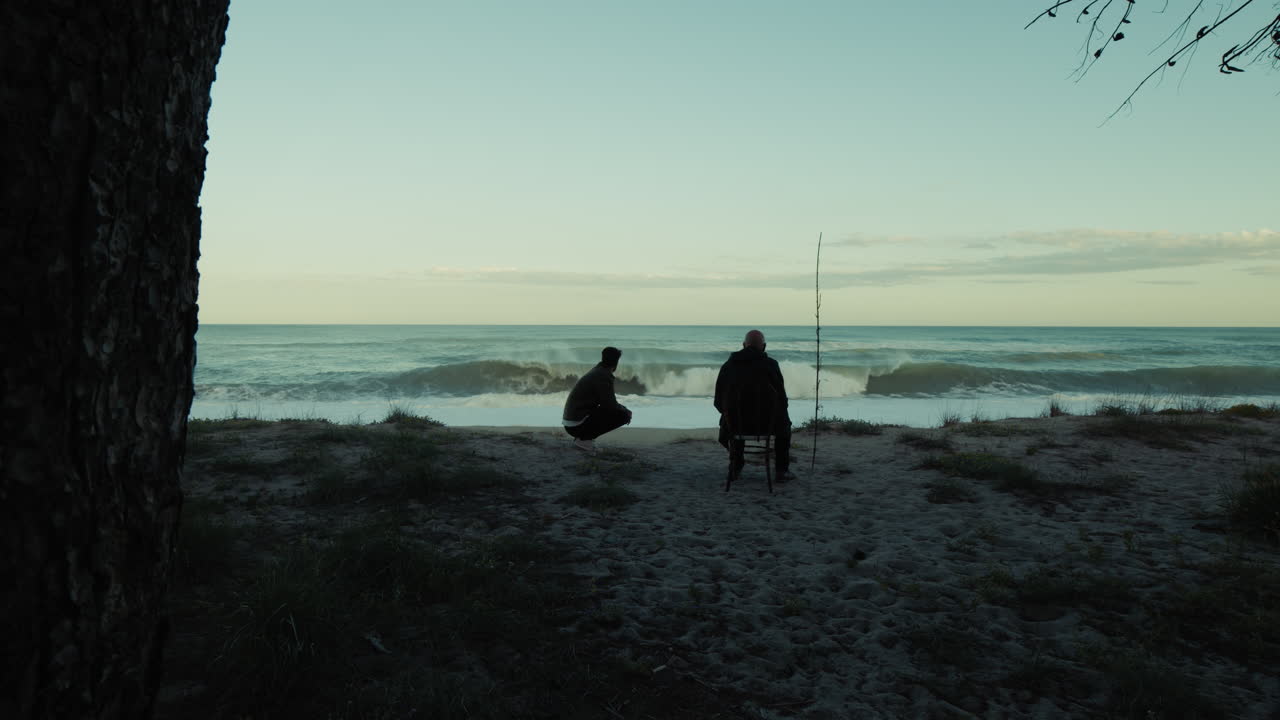 Silhouette of two people watching the strong ocean waves crash in the morning