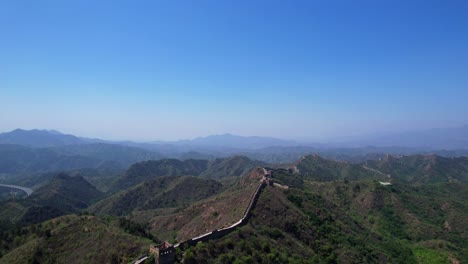 aerial rising shot of how great wall of china is lost in infinity through mountains on sunny day