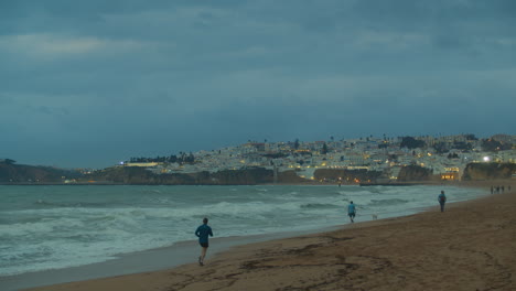 Olas-Del-Océano-Por-La-Tarde-Y-Luces-De-La-Ciudad-En-Portugal