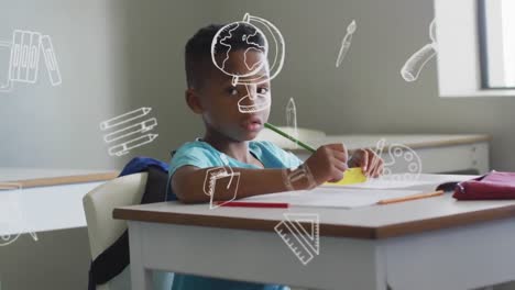 Animation-of-school-icons-over-happy-african-american-schoolboy-working-at-desk-in-class