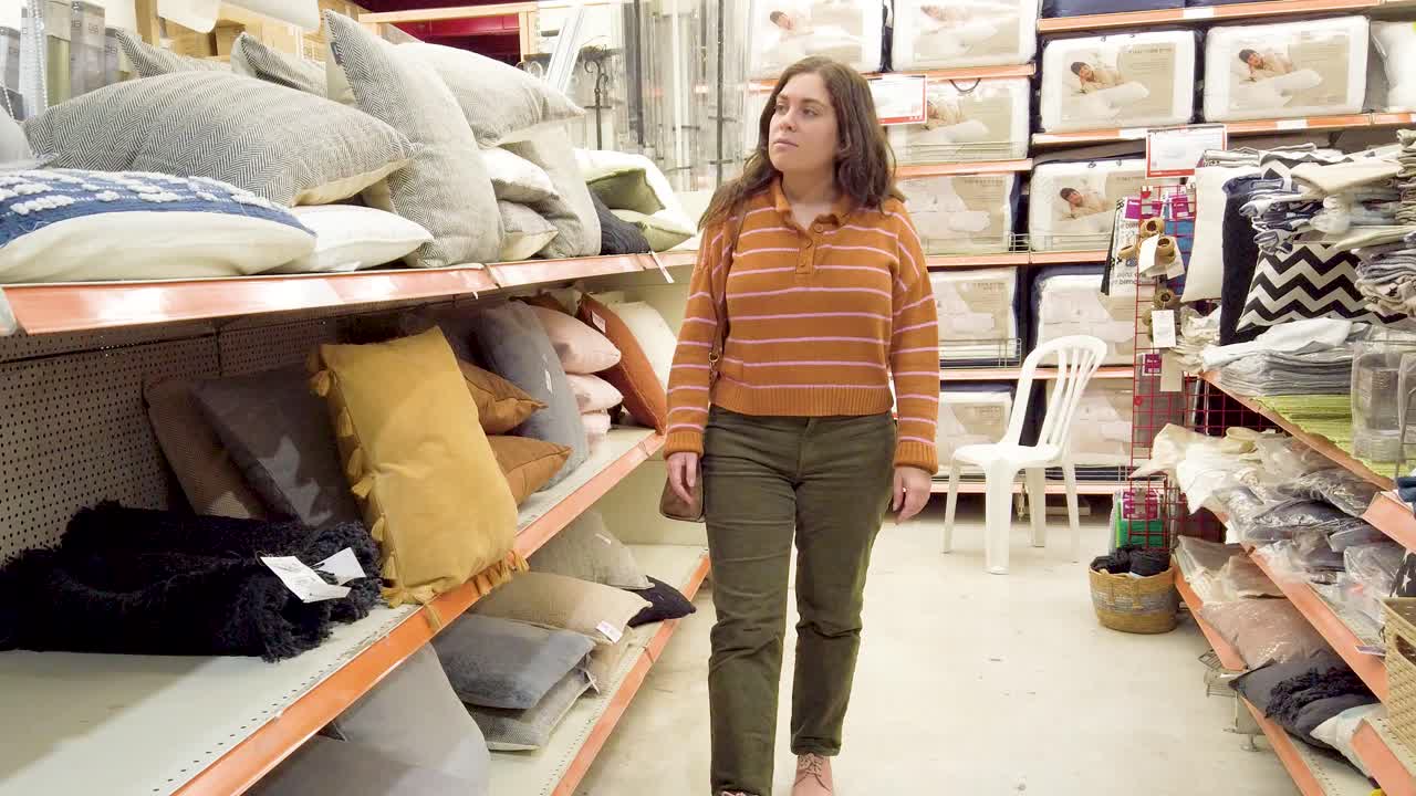 A woman is shopping for pillows in a store