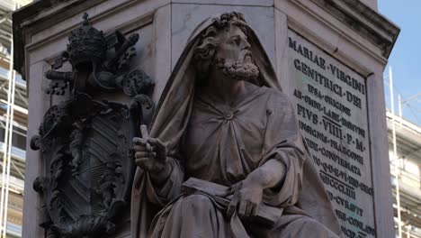 close-up of an apostle statue from the column of the immaculate conception in rome, italy, featuring papal coat of arms and latin inscription in a religious setting.