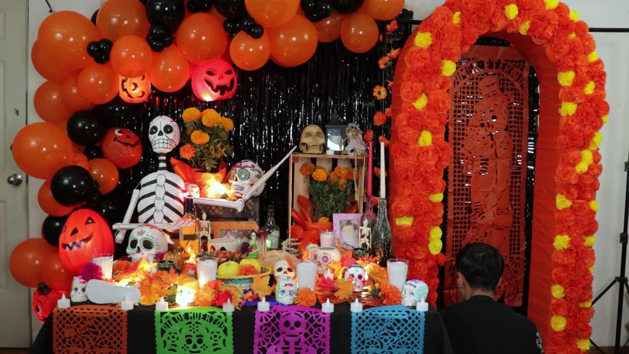 Mexican man turning on chain lights on decorated Halloween altar.
