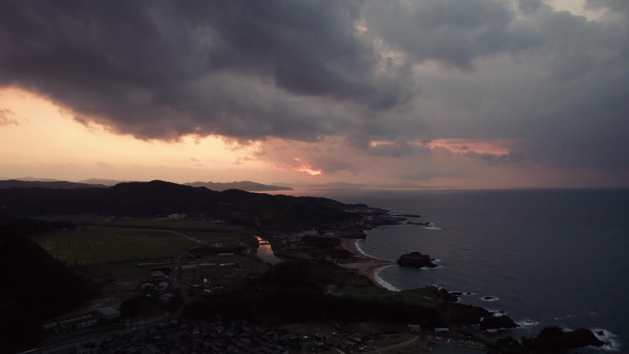dramático atardecer aéreo sobre el mar de japón playa montaña horizonte drones nubes se mueven en cámara lenta sobre kyotango