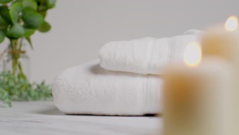 person putting down towels at relaxing spa day with lit candles with green leaved plant