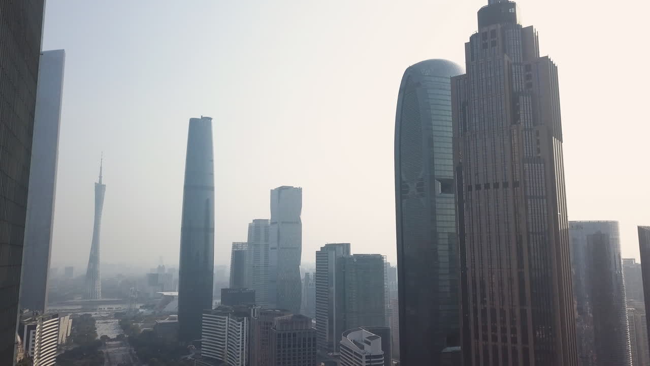 Guangzhou, China. Aerial shot of downtown Central Buildings District (CBD) with the reveal of Canton Tower, Central Park and Pearl river on a sunny day in the afternoon