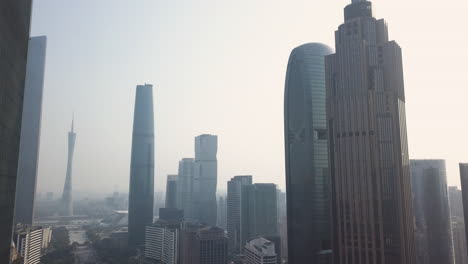 guangzhou, china. aerial shot of downtown central buildings district (cbd) with the reveal of canton tower, central park and pearl river on a sunny day in the afternoon