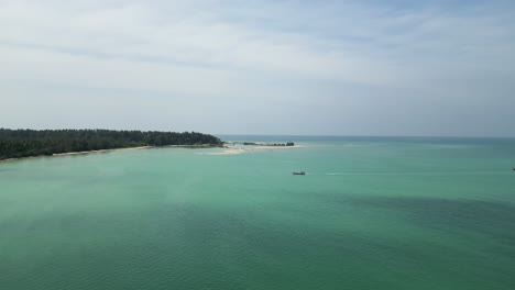 mango bay in ko tao island thailand with long tail boat approaching shore, aerial approach shot