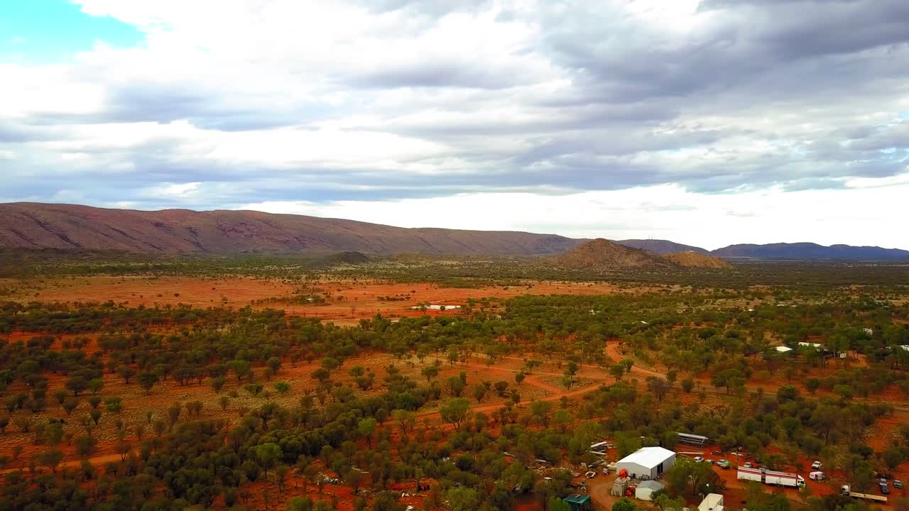 The Central Australian Outback. Cinematic track forwards and pan right, over roads, local flora and settlements. Filmed on a DJI Mavic Pro on a Camel Farm near Alice Springs.