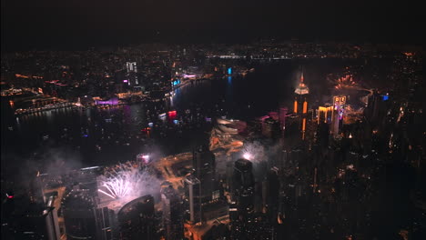 Elaborado-Espectáculo-De-Fuegos-Artificiales-Sobre-El-Horizonte-De-La-Isla-De-Hong-Kong-Por-La-Noche,-Tiro-Aéreo-De-Gran-Angular