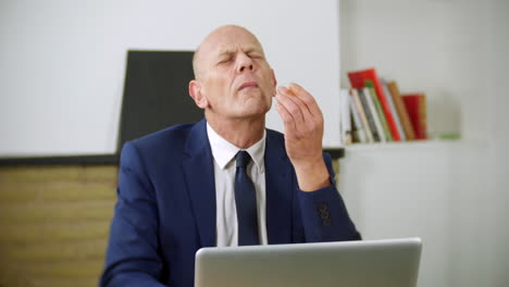 A-tired-mature-businessman-is-working-on-his-laptop-in-his-home-office