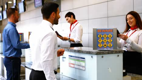 dos empleadas del aeropuerto chequeando pasaportes e interactuando con los pasajeros en el mostrador de facturación