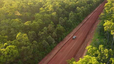 aerial clip of 4x4 driving in remote outback australia, late afternoon on red dirt road, clip two