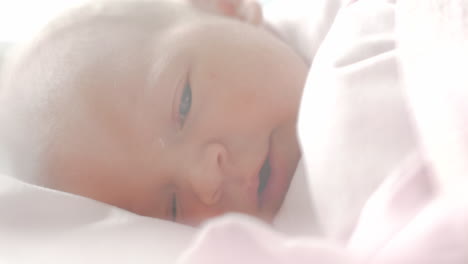 newborn baby with blue eyes falling asleep