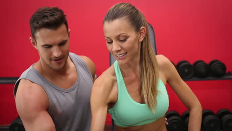 mujer en forma levantando pesas con entrenador