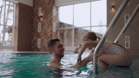 dad is teaching his little daughter to swim in pool happy childhood moments