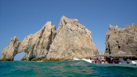 view from boat of rock formations with a natural arch formation located on the beach