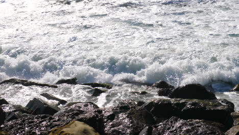 un'onda dell'oceano che si infrange da vicino al rallentatore contro le rocce di una spiaggia della california sulla costa