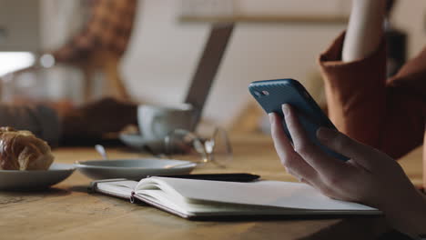 cerca de las manos de una mujer de negocios usando un teléfono inteligente en una cafetería bebiendo café enviando mensajes de texto leyendo mensajes de correo electrónico conectándose a internet por teléfono móvil