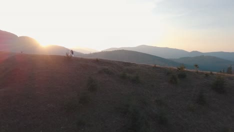 Newlyweds-stand-on-a-high-slope-of-the-mountain.-Groom-and-bride.-Aerial-view