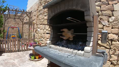 Rotisserie-Chicken-rotating-in-a-wood-and-charcoal-fire-brick-bbq-grilling-in-timelapse