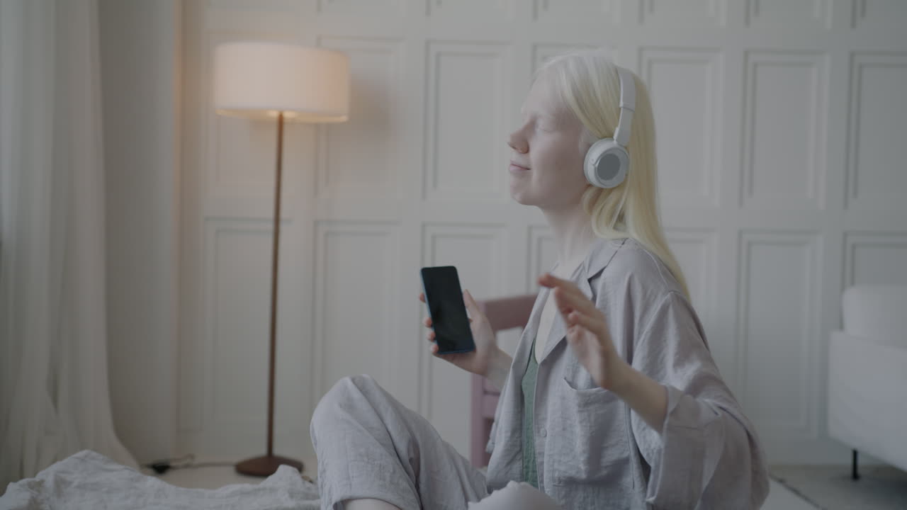 Woman listening to music and dancing on bed