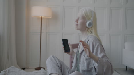 woman listening to music and dancing on bed