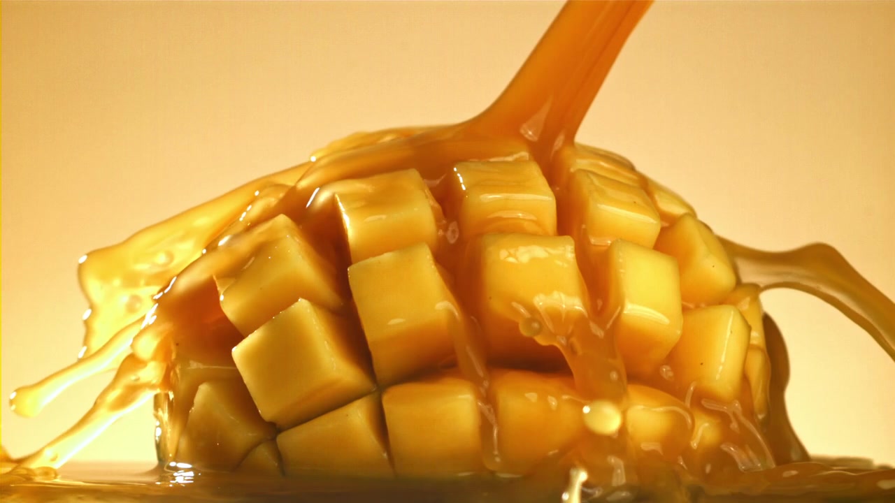 Versamento al rallentatore di succo di mango su cubetti freschi.