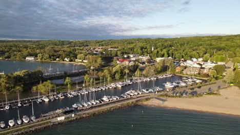 suttons bay pier with moored sail boats and sandy beach, aerial fly away view